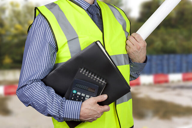 A surveyor with a file, a notepad and a calculator